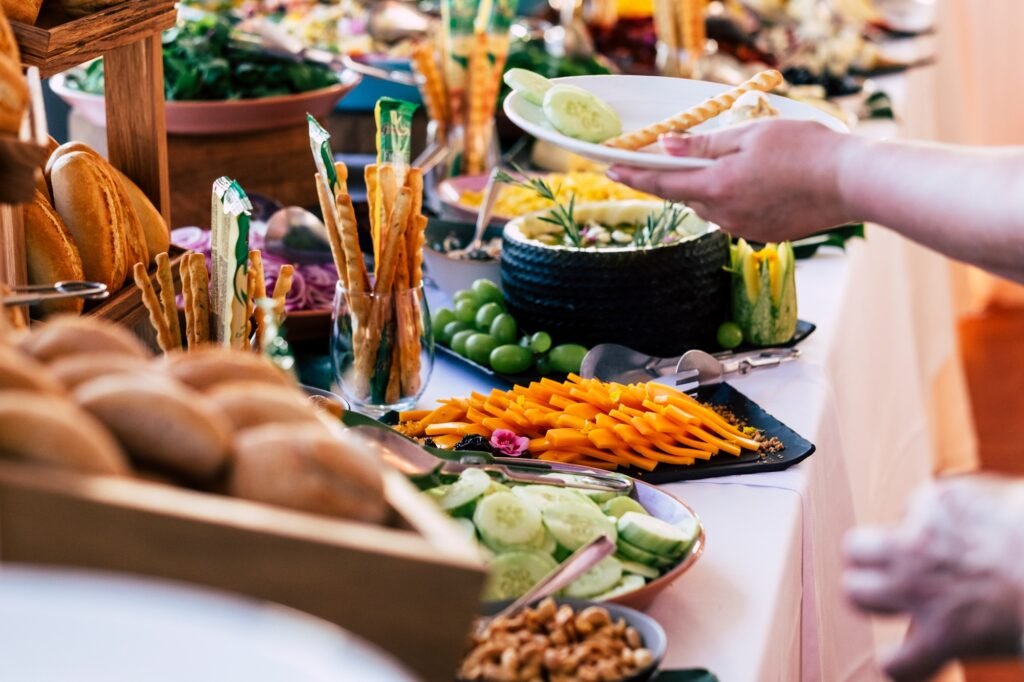 Close up of people taking food from table at event party with catering self service